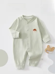 Detail of light green ribbed cotton baby romper featuring embroidered house and snap buttons