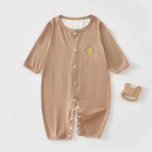 Close-up of brown baby romper with smiley face print and wooden bear teething toy