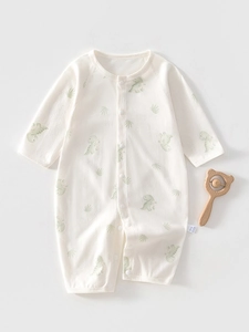 Detailed view of baby cotton long sleeve romper with dinosaur print and wooden rattle toy