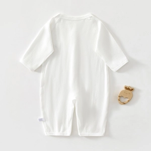 Macro shot of white waffle knit cotton baby romper showing soft texture and fabric detail