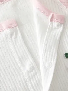Detail of food-grade POM resin snap buttons on white waffle knit baby romper fabric