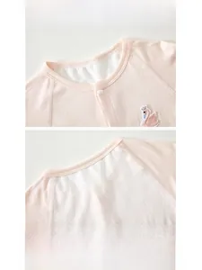 Detail of pink cotton baby romper featuring mesh back panels and swan embroidery decor