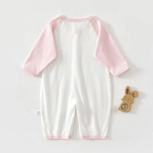 Close-up of pink waffle texture cotton baby romper with logo tag and wood rabbit toy