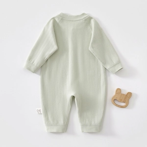 Detail of light green baby romper in ribbed knit cotton with a wooden bunny teether