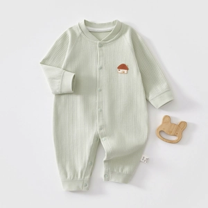 Close-up of baby romper with ribbed cotton texture, house embroidery and wooden teether