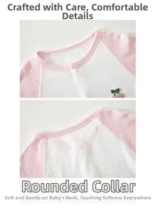 Detail of pink waffle knit baby romper featuring cherry embroidery and bound neckline