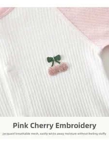 Close-up of baby romper showing breathable jacquard mesh fabric and cherry embroidery
