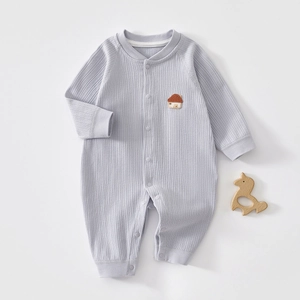 Detail of baby ribbed cotton romper in light purple with house embroidery on grey background