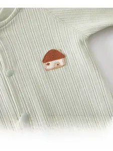 Detail of light green baby romper featuring ribbed fabric and house embroidery