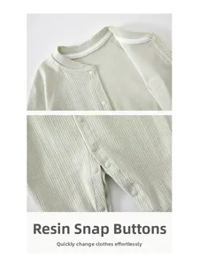 Detail view of cotton baby romper showing ribbed texture fabric and resin snap closures
