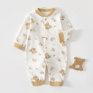 Détail d'un pyjama bébé en coton avec imprimé ours et anneau de dentition en bois