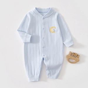 Detail of light blue infant romper with embroidered bunny and moon on textured cotton fabric