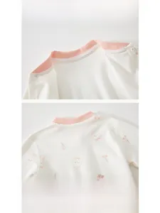 Détail de la combinaison bébé en coton avec encolure bordée et imprimé lapin cerise