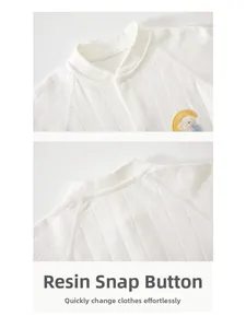 Detail of white quilted baby bodysuit featuring resin snaps and elephant moon embroidery