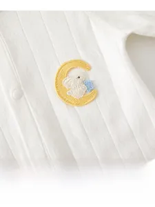 Detail of white ribbed baby romper featuring rabbit and moon embroidery with snap buttons