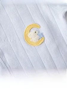 Detailed macro shot of blue cotton fabric with moon and bunny embroidery on baby onesie