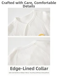 Detailed close-up of white knitted cotton infant bodysuit with soft jacquard texture