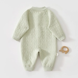 Detail of light green quilted baby romper with embossed star and moon pattern texture