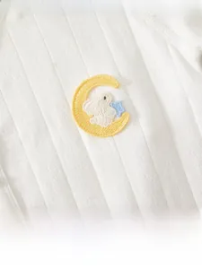 Close-up of white jacquard baby romper with embroidered moon, rabbit and star detail