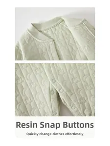 Close-up of baby romper resin snaps with moon and star embossed quilted green fabric