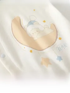 Close-up of baby romper with sleeping bear on moon print and white snap buttons