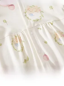 Close-up of baby romper fabric with pink rabbit prints and white resin snap buttons