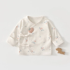 Détail d'un haut kimono en coton pour bébé avec imprimé floral et petits nœuds rubans