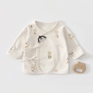 Détail d'un haut kimono pour bébé en coton bio avec imprimés panda et pingouin mignons