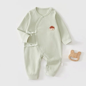Détail d'un body bébé en coton côtelé doux avec broderie et fermeture à nouer sur le côté