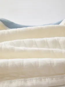 Détail macro du tissu matelassé en coton doux pour vêtements bébé avec texture gaufrée