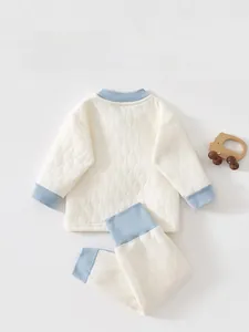 Détail d'un ensemble thermique pour bébé matelassé avec bord-côte bleu et jouet en bois