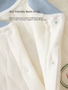 Close-up of eco-friendly resin snaps and quilted cotton fabric on newborn baby romper
