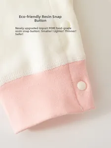 Macro detail of safe POM resin snaps on soft pink and beige knitted cotton baby bodysuit