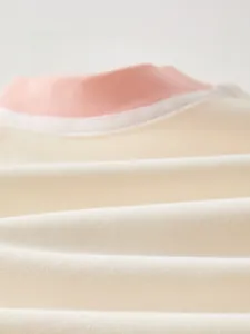 Macro detail of breathable soft fine cotton fabric on long sleeve baby jumpsuit