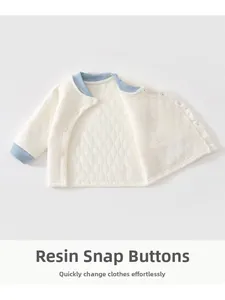 Détail d'une veste matelassée pour bébé avec boutons pression en résine et texture