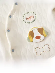 Détail du haut matelassé pour bébé avec boutons-pression bleus et motif chiot