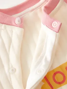 Detailed close-up of eco-friendly resin snap buttons on pink quilted baby romper fabric