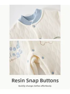 Close-up of quilted cotton baby romper featuring blue resin buttons and neck detail