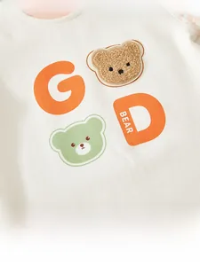 Detail of baby knit romper featuring fuzzy bear patch and colorful letter prints