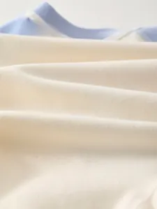 Dettaglio macro del tessuto in cotone traspirante azzurro e beige per tutine neonato