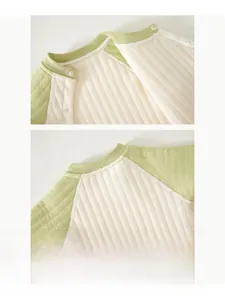 Detail of baby quilted bodysuit neckline with white snap buttons and green piping