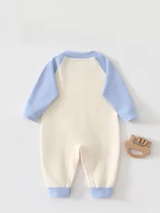 Dettaglio di pagliaccetto per neonati in morbida maglia con maniche raglan e retro patchwork