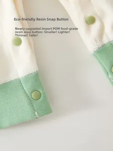 Détail de pressions en résine écologique sur un body bébé en coton doux avec bord vert