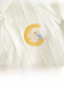 Macro detail of soft cotton infant clothes with delicate rabbit and moon embroidery