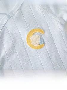 Detailed close-up of light blue baby cotton fabric featuring moon and rabbit embroidery