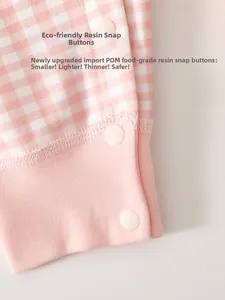Detail of eco-friendly resin snaps on pink gingham infant clothing with soft fabric texture