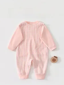 Close-up of pink and white checkered baby onesie with ribbed cuffs and cotton texture