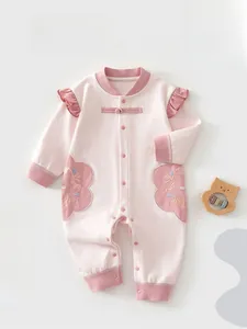 Detail of baby romper featuring Chinese frog button and floral embroidery on pink cotton