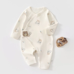 Detail of baby bear astronaut cotton onesie showing snaps and wooden teether