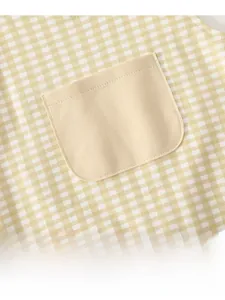 Close-up of yellow plaid baby overalls fabric with detailed beige front pocket stitching
